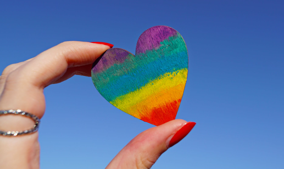 Hand holding rainbow paper heart.