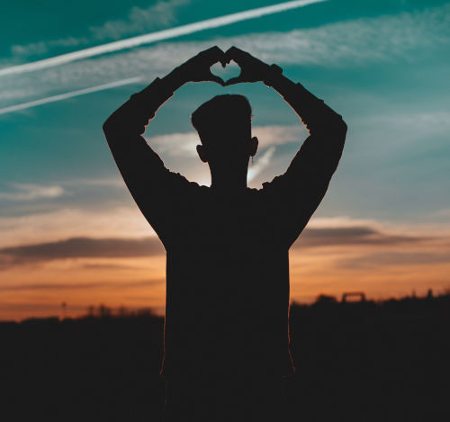 Man in silhouette making heart shape with hands